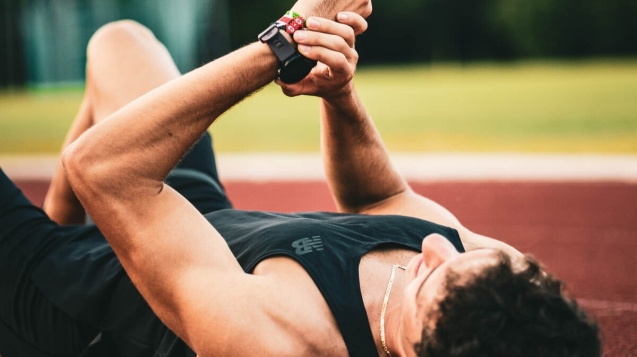 jacopo peron atleta sdraiato sulla pista di atletica che schiaccia il pulsante di stop dell'orologio garmin al termine di un allenamento tosto